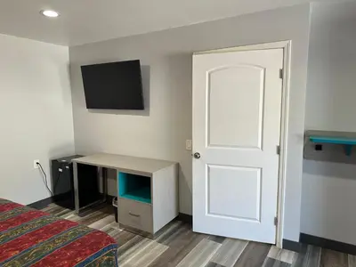 a room with a bed and a door and a tv at Sahara Inn - Los Angeles in Los Angeles