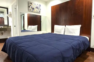 a bedroom with a blue bed with a wooden headboard at Century Motel Buena Park Anaheim I-5 in Buena Park