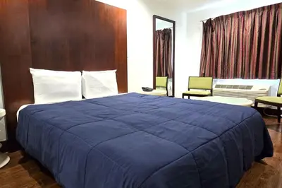 a hotel room with a large bed with a blue blanket at Century Motel Buena Park Anaheim I-5 in Buena Park