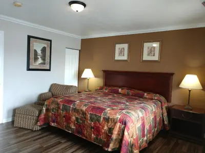 a bedroom with a bed and a chair and two lamps at Bartlett Motel in Lomita