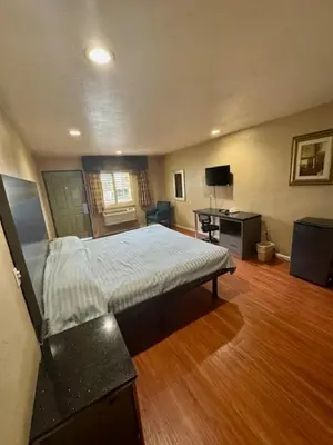 a bedroom with a large bed and a wooden floor at Golden Star Inn in San Bernardino
