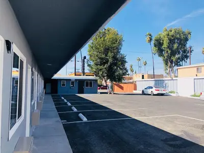a parking lot next to a building with a car at New Casa Motel Los Angeles in Los Angeles