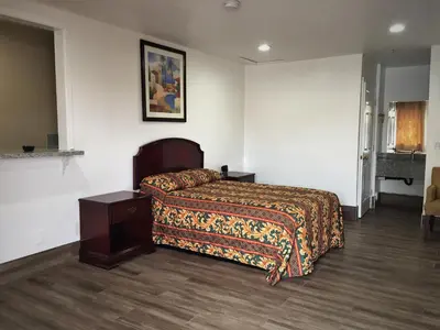 a hotel room with a bed and a night stand at Palm Inn Motel - Montclair in Montclair