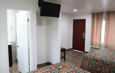 a room with two beds and a flat screen tv at Palm Inn Motel - Montclair in Montclair