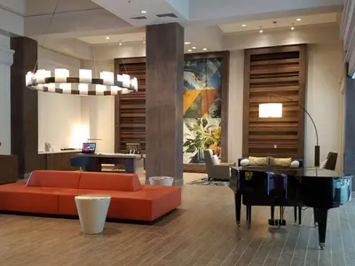 a living room with an orange couch and a piano at Embassy Suites by Hilton Brea - North Orange County in Brea