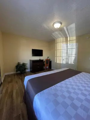 a bedroom with a bed and a flat screen tv at Palm Tropics Motel in Glendora