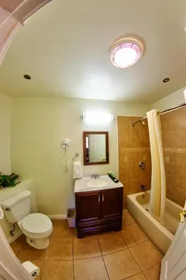 a bathroom with a toilet and a sink and a tub at Palm Tropics Motel in Glendora