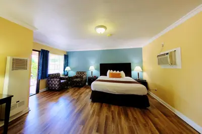 a bedroom with a bed and a couch and a chair at Palm Tropics Motel in Glendora