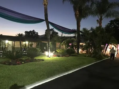a person walking down a street next to a house with palm trees at Palm Tropics Motel in Glendora
