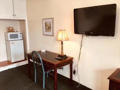 a room with a desk and a television on a wall at Los Feliz Hotel in Glendale