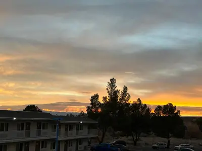 a sunset over a building with a parking lot at Motel 6 Victorville in Victorville