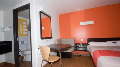 a room with a bed and a table and a bed and a bathroom at Motel 6 Victorville in Victorville