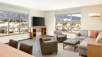 a living room with a couch and chairs and windows at Hyatt Place Pasadena in Pasadena