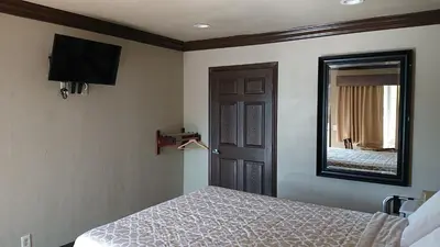 a bedroom with a bed and a mirror and a door at Santa Ana Travel Inn in Santa Ana