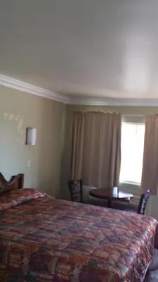 a bedroom with a bed and a table and a window at Santa Ana Travel Inn in Santa Ana