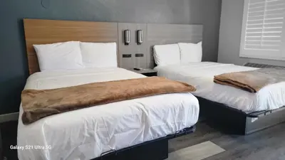 a hotel room with two beds with white sheets at Value Inn Hollywood in Los Angeles