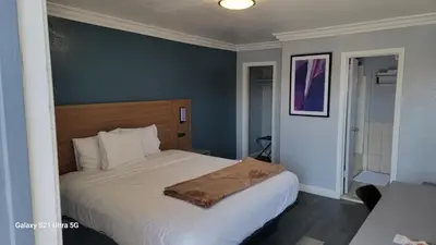 a bedroom with a white bed with a blue wall at Value Inn Hollywood in Los Angeles