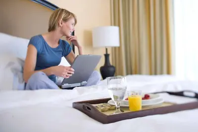a woman sitting on a bed with a tray of food at DoubleTree Suites By Hilton Anaheim Resort/Convention Center in Anaheim