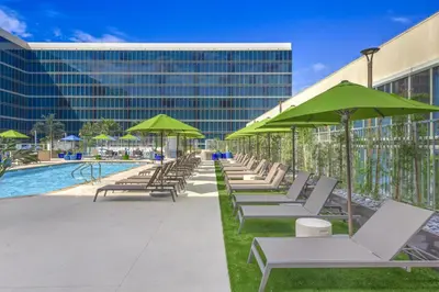 a row of lounge chairs with green umbrellas next to a pool at Hilton Anaheim in Anaheim