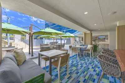 a restaurant with tables and chairs and green umbrellas at Hilton Anaheim in Anaheim