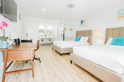 a hotel room with two beds and a desk and a desk at The Belmont Shore Inn in Long Beach
