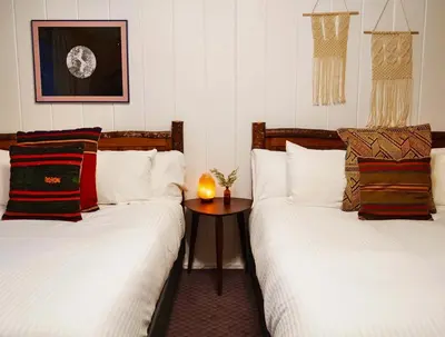 two beds in a room with a table between them at Grand Pine Cabins in Wrightwood