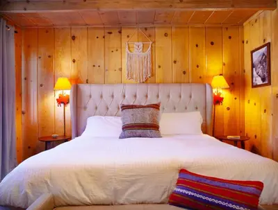 a bedroom with a large white bed with wooden walls at Grand Pine Cabins in Wrightwood