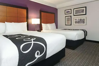 two beds in a hotel room with purple walls at La Quinta Inn & Suites by Wyndham Ontario Airport in Ontario