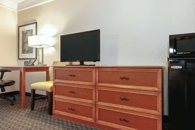 a hotel room with a dresser with a television on it at La Quinta Inn & Suites by Wyndham Ontario Airport in Ontario