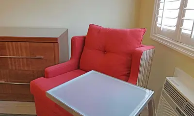 a red chair with a table in a room at Del Mar Motel in Rosemead