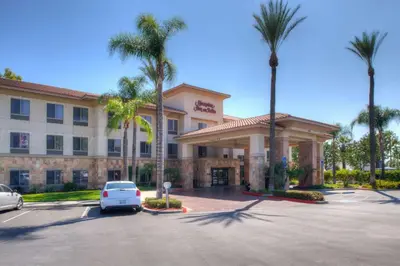 a car parked in front of a hotel with palm trees at Hampton Inn & Suites Ontario in Ontario