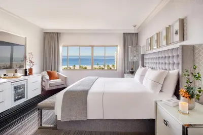 a bedroom with a large white bed and a view of the ocean at Huntley Santa Monica Beach in Los Angeles