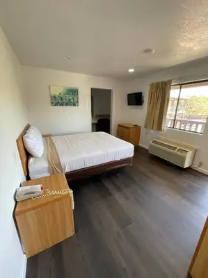 a bedroom with a bed and a desk and a window at Palms Inn & Suites in Palmdale