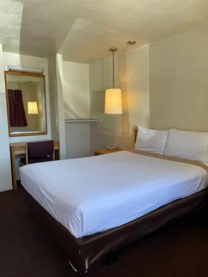a large white bed in a hotel room at Palms Inn & Suites in Palmdale