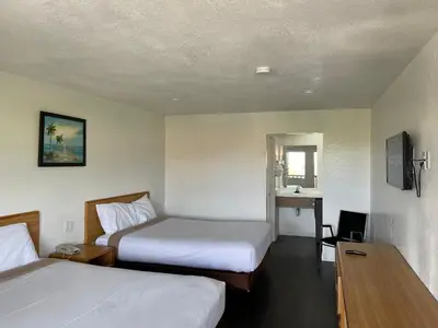 a hotel room with two beds and a desk at Palms Inn & Suites in Palmdale