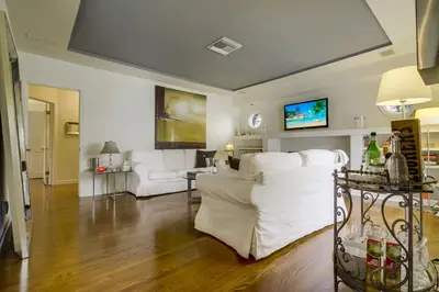 a living room with white couches and a tv at A Touch of Cape Cod in West Hollywood in Los Angeles