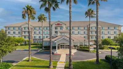 a hotel with palm trees in front of it at Hilton Garden Inn Ontario Rancho Cucamonga in Rancho Cucamonga