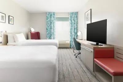 a hotel room with two beds and a desk with a tv at Hilton Garden Inn Ontario Rancho Cucamonga in Rancho Cucamonga