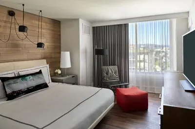 a bedroom with a bed and a chair and a window at Kimpton Hotel Palomar Los Angeles Beverly Hills by IHG in Los Angeles