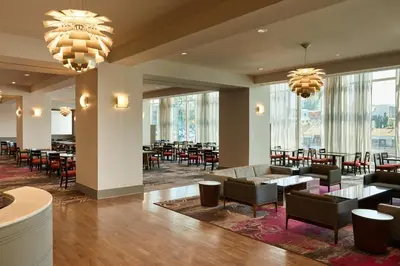 a restaurant with tables and chairs and large windows at Loews Hollywood Hotel in Los Angeles