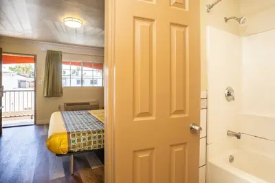 a door to a bedroom with a bed and a tub at Economy Inn Hollywood in Los Angeles