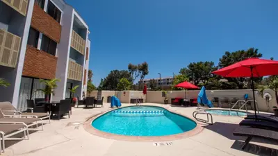 a pool with chairs and umbrellas at a hotel at Holiday Inn Express Port Hueneme by IHG in Port Hueneme