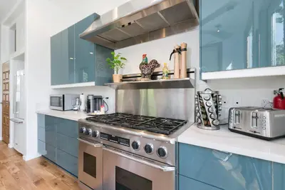 a kitchen with a stove and blue cabinets at Stunning 2-Bedroom Home near Downtown Culver in Los Angeles