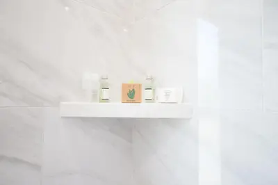 a white shelf in a white bathroom with some products at Wilshire Crest Hotel in Los Angeles