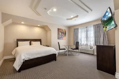 a bedroom with a bed and a desk and a television at Wilshire Crest Hotel in Los Angeles