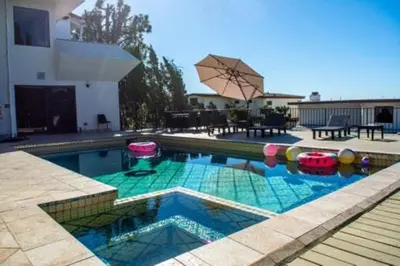 a swimming pool with an umbrella in a house at Hollywood Hills private room in Los Angeles
