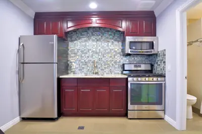 a kitchen with red cabinets and a stainless steel refrigerator at Crystal Lodge Motel in Ventura