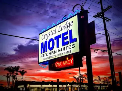 a sign for a motel with a sunset in the background at Crystal Lodge Motel in Ventura