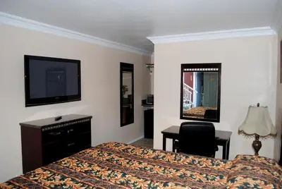 a bedroom with a bed and a desk and a television at Crystal Lodge Motel in Ventura