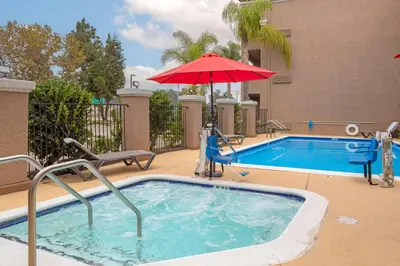 a swimming pool with a red umbrella and a swimming pool at Quality Inn & Suites Camarillo-Oxnard in Camarillo